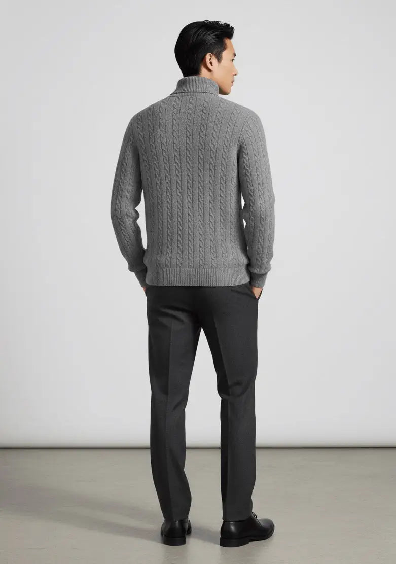 Man wearing a gray cable knit sweater and black pants against a white background