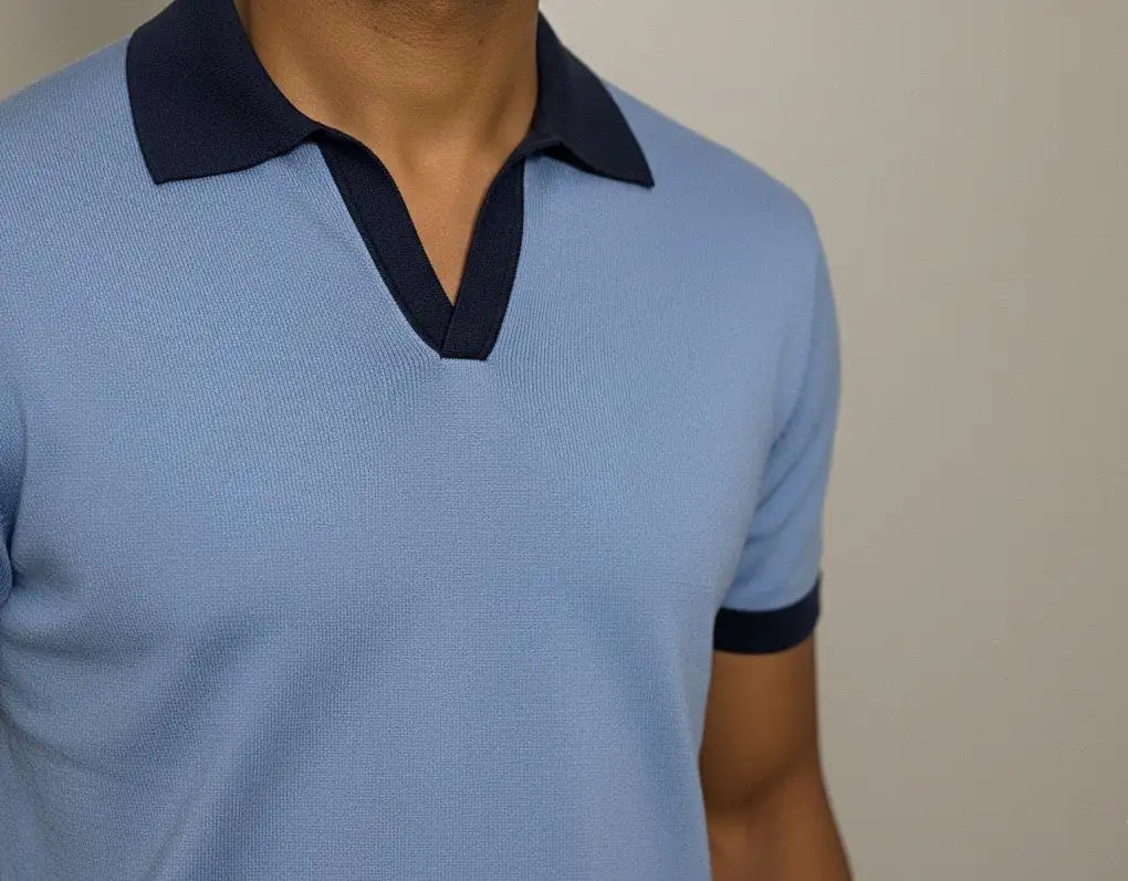Light blue polo shirt with dark collar and cuffs on a neutral background