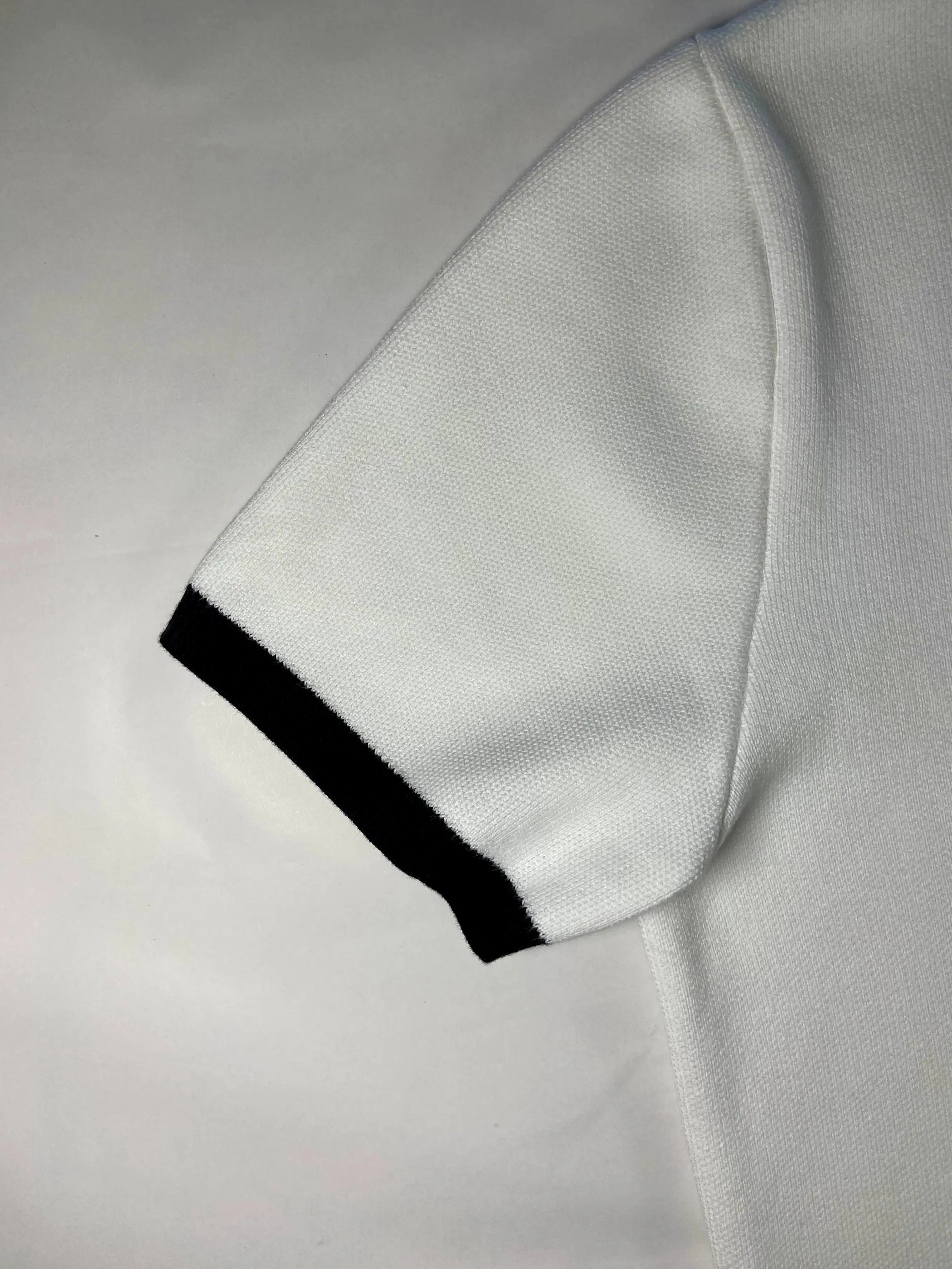 Close-up of a white textured fabric sleeve with a black ribbed trim at the cuff, laid flat on a white background.