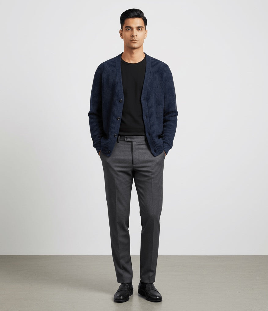 Man wearing a Blue RWS extra fine Merino Wool knitted cardigan, black shirt, and gray pants against a white background